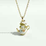 Teapot-shaped pendant with a mouse figure on a gold chain against a white background