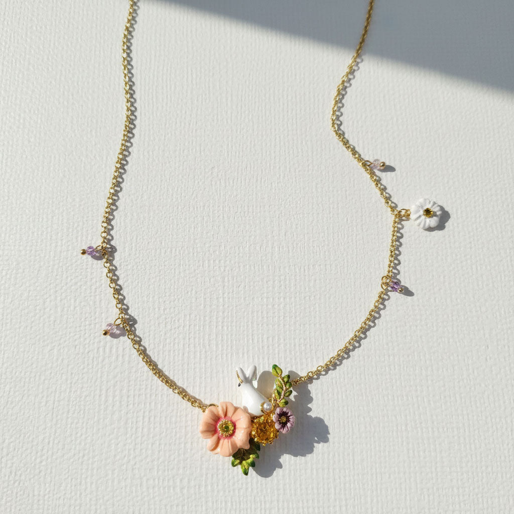 Delicate gold necklace with floral pendants on a light background