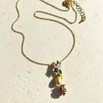 Gold necklace with a mouse and flower pendant on a light beige background