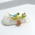 Colorful bird-shaped necklace with floral and berry charms on a white stone background