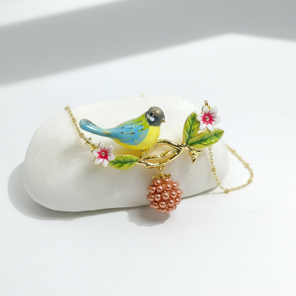 Colorful bird-shaped necklace with floral and berry charms on a white stone background