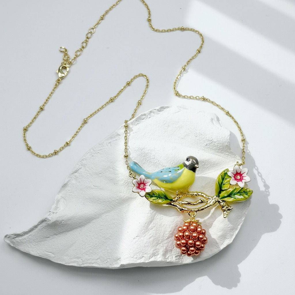 Necklace with a bird and floral pendant on a white leaf