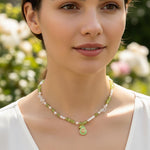 Woman wearing a green necklace with a pendant against a blurred natural background