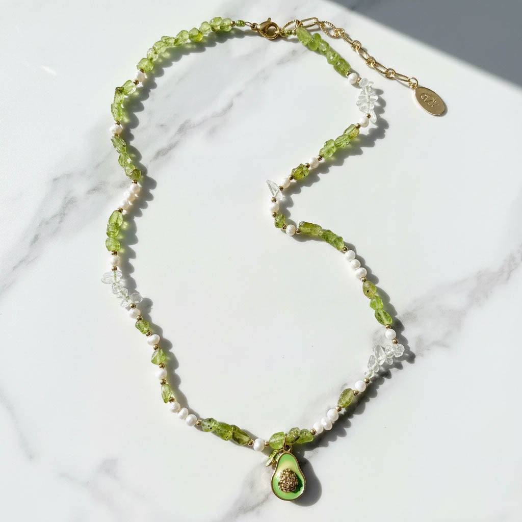 Necklace with green beads and a pendant on a marble surface