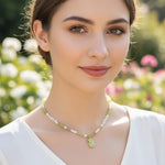 Woman wearing a necklace with a green pendant against a blurred natural background