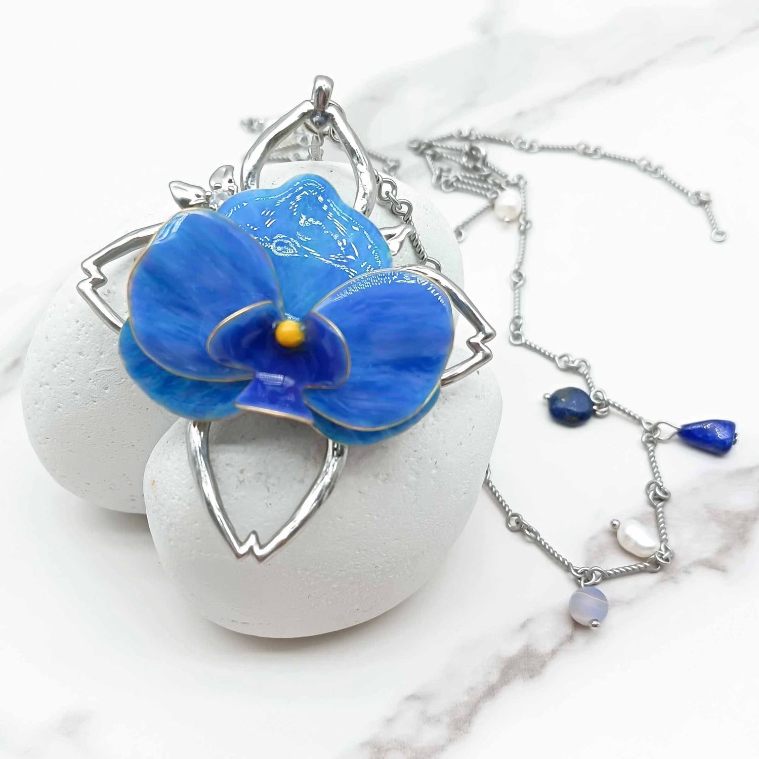 Blue flower pendant on a white stone with a silver chain necklace.