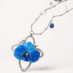 Necklace with a blue flower pendant on a white background