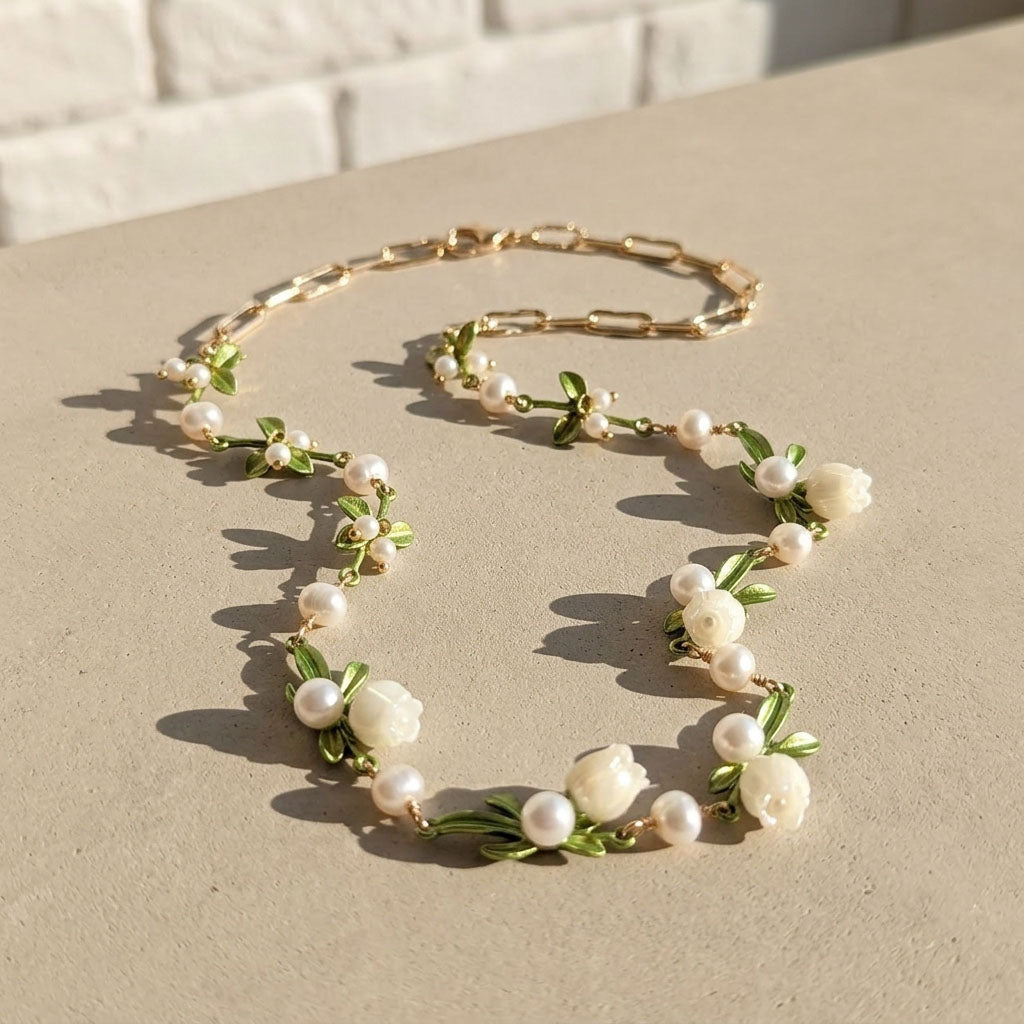 Hand carved mother of pearl floral necklace with enamel leaves on neutral background
