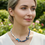 Woman wearing a blue floral necklace with a blurred garden background