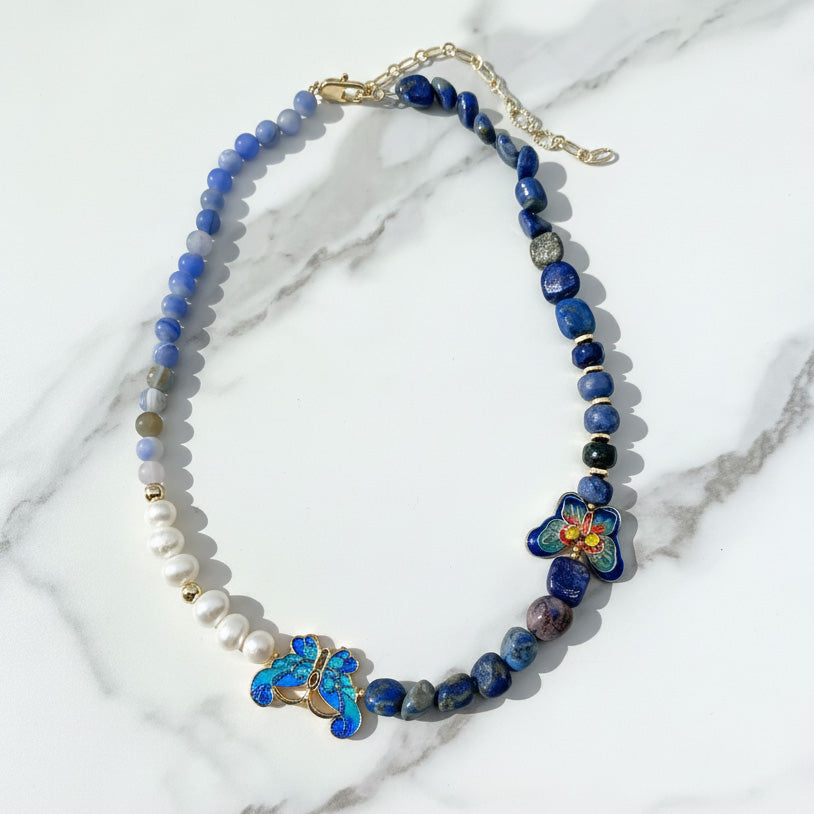 Necklace with blue beads and floral elements on a marble background