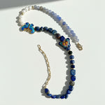 Necklace with blue beads and floral pendants on a white background