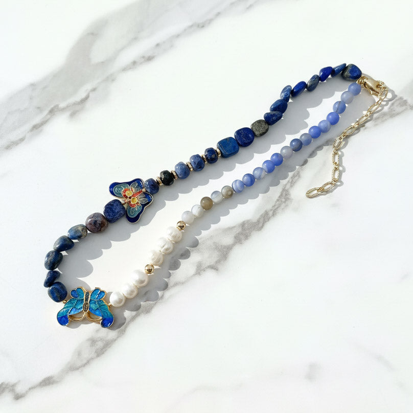 Beaded necklace with blue flowers and pearls on a marble surface