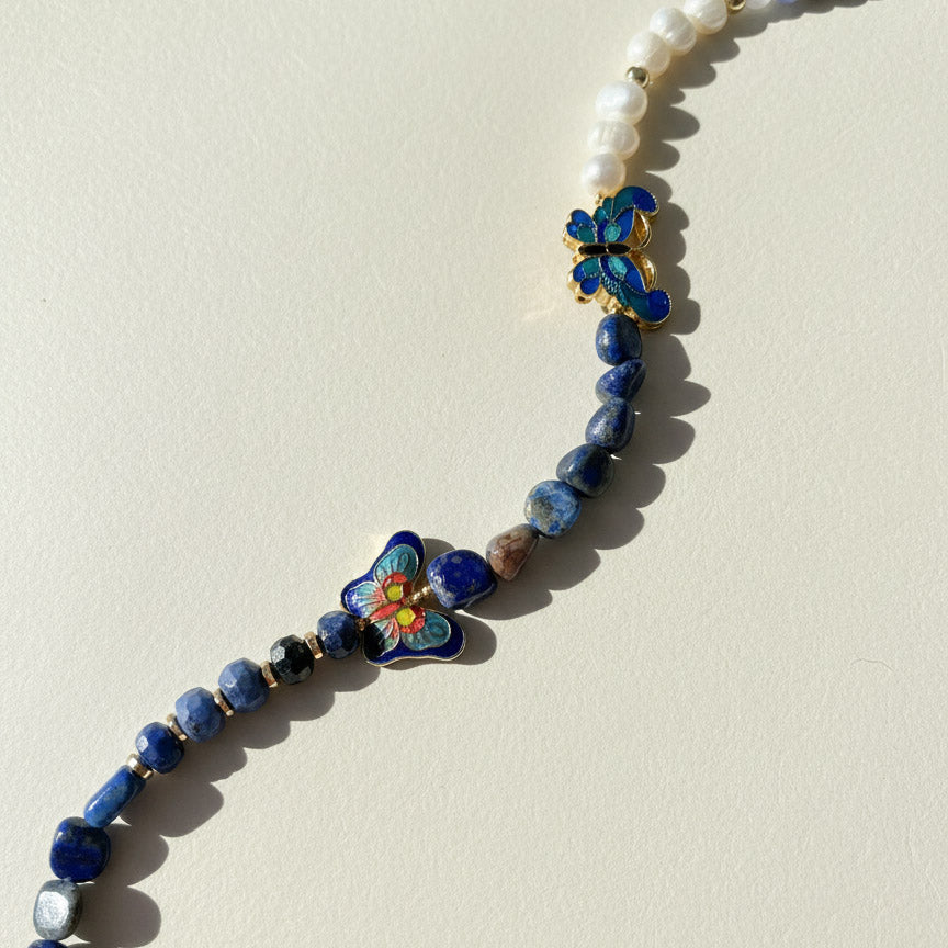 Necklace with blue beads and floral elements on a beige background