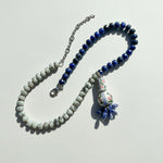 Beaded necklace with a decorative pendant on a light gray background