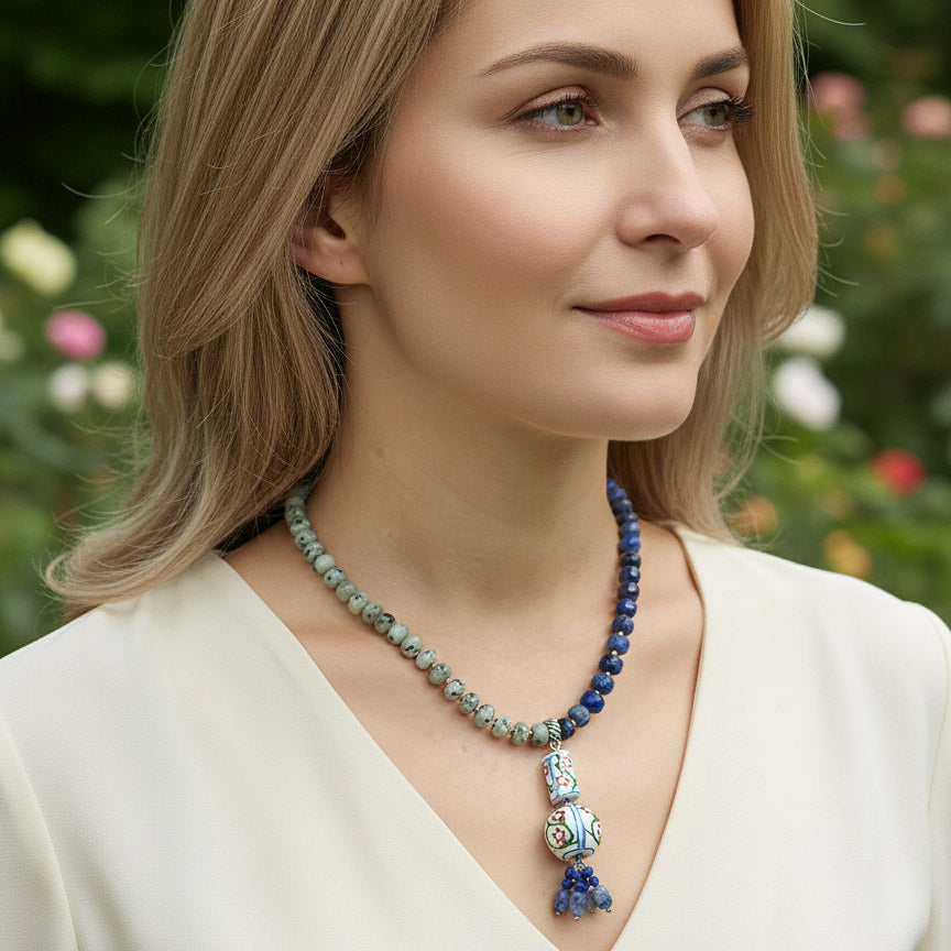Woman wearing a beaded necklace with a pendant outdoors