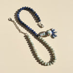Necklace with blue and green beads on a beige background