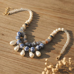 Necklace with pearls and blue ceramic beads on a wooden surface