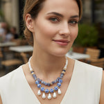 Woman wearing a pearl and blue beaded necklace in an outdoor setting