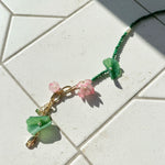Beaded floral necklace on tiled surface with soft shadow.