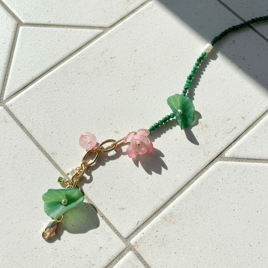 Beaded floral necklace on tiled surface with soft shadow.