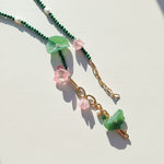 Close-up of malachite leaf and pink flower beaded necklace.