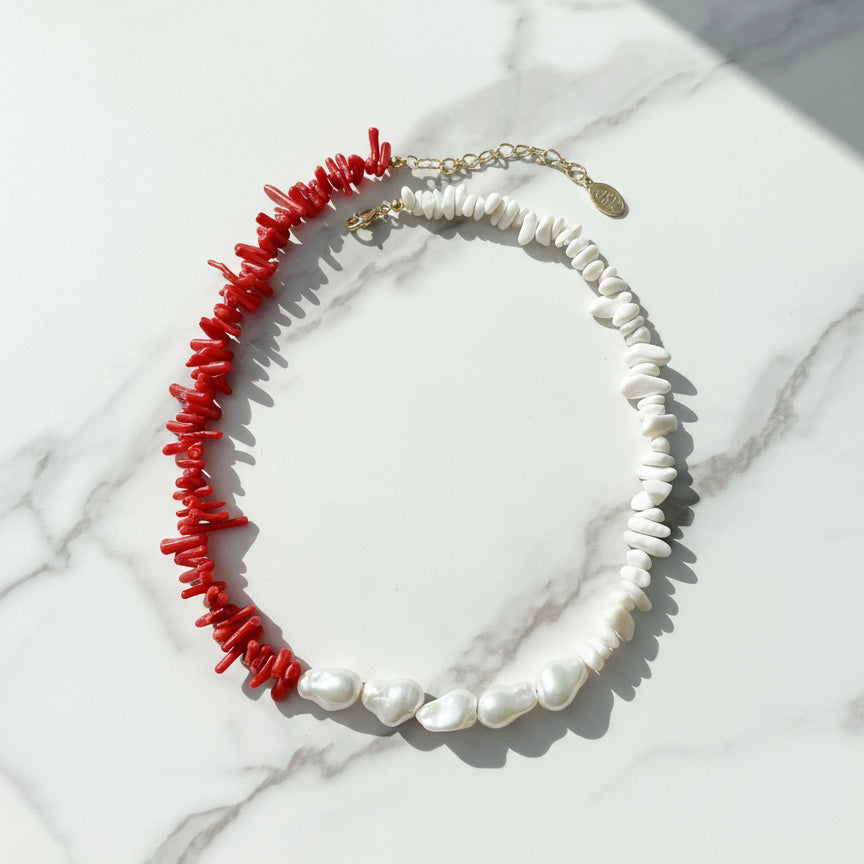 Necklace with red coral and white pearls on a marble surface