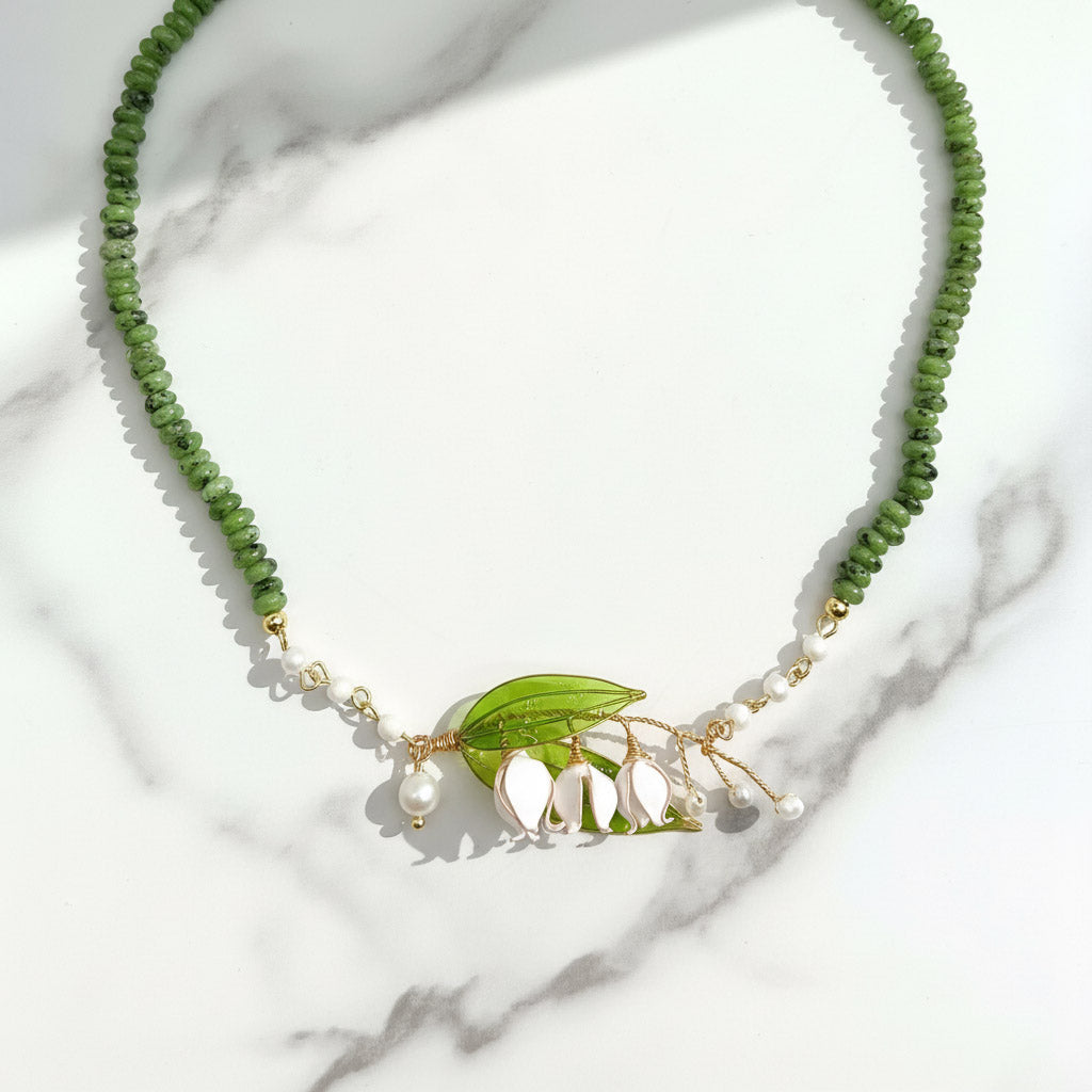 Botanical necklace with hand-painted lily of the valley pendant, freshwater pearls, and green stone beads.