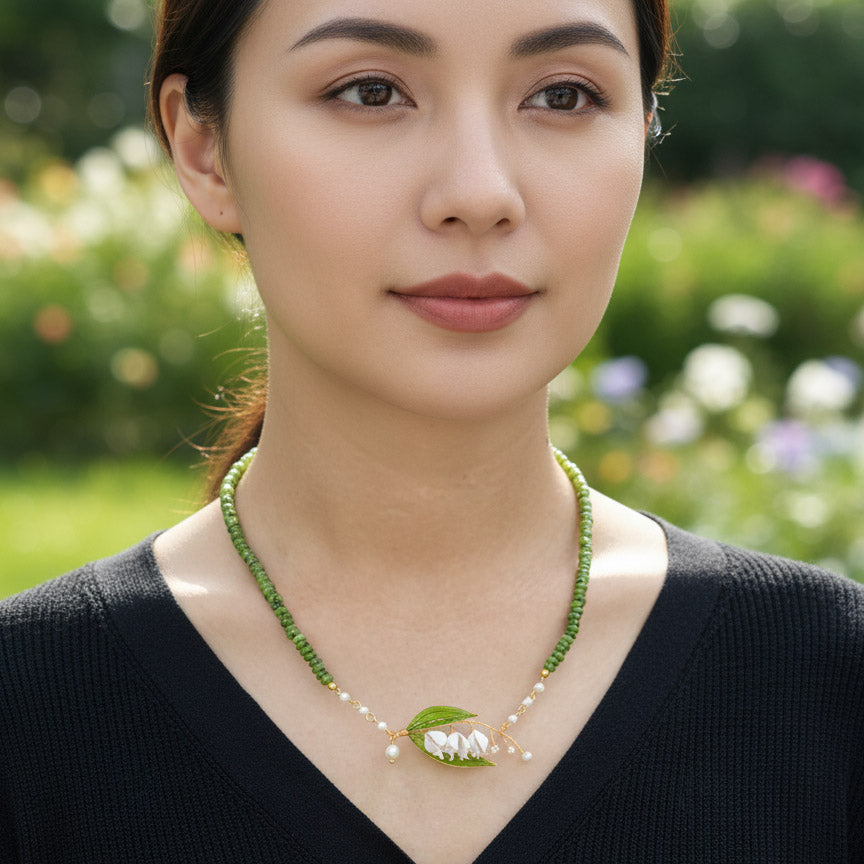 Woman wearing a green beaded necklace with a leaf design in a garden setting