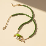 Lily of the valley necklace with green gemstone beads, resin flower pendant, and pearl accents.