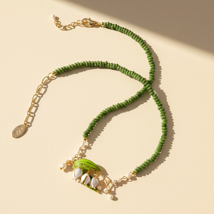 Lily of the valley necklace with green gemstone beads, resin flower pendant, and pearl accents.