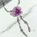 Necklace with a purple flower pendant on a marble surface