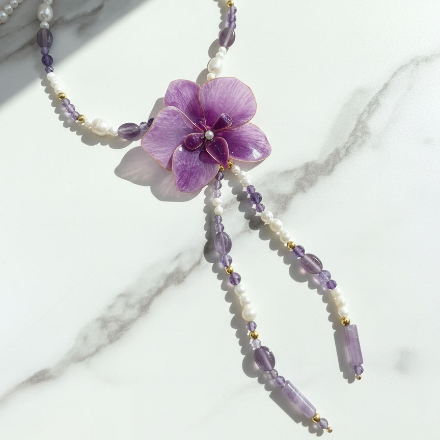 Necklace with a purple flower pendant on a marble surface