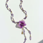 Necklace with a purple flower pendant on a white background