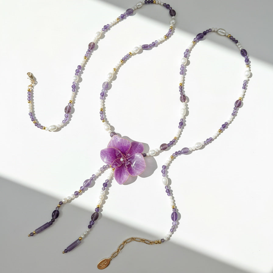 Beaded necklace with a purple flower pendant on a light gray background