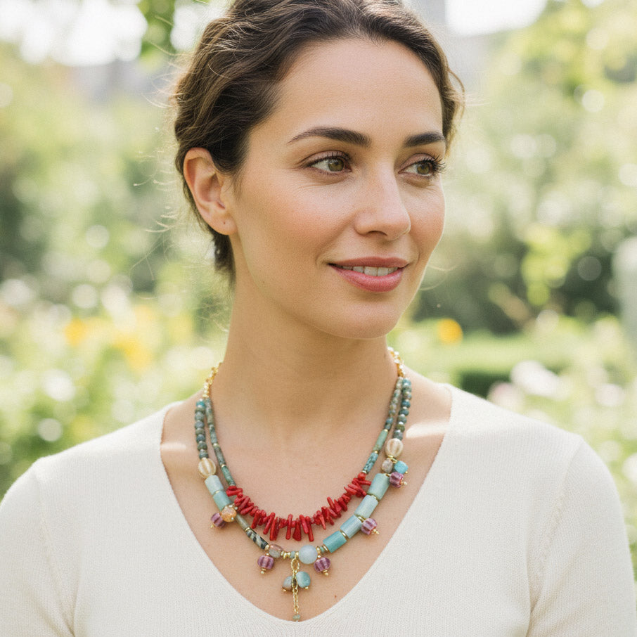 Model wearing coral and turquoise gemstone necklace outdoors.