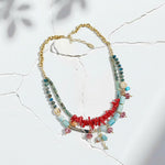 Multicolored beaded necklace with red accents on a light background