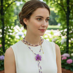 Woman wearing a necklace with a purple flower pendant in a garden setting