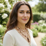 Model wearing long beaded necklace with natural stones and carved fish pendant outdoors