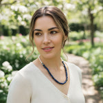 Woman wearing a blue necklace in a garden setting