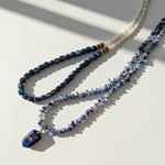 Two beaded necklaces on a light surface with shadows