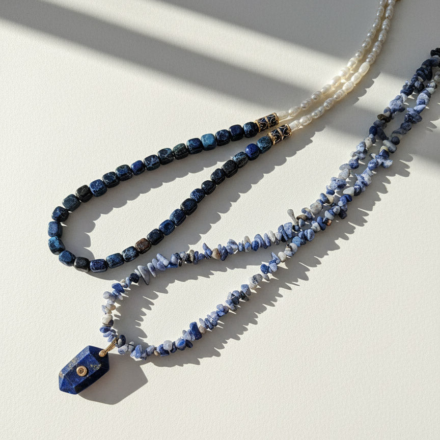 Two beaded necklaces on a light surface with shadows
