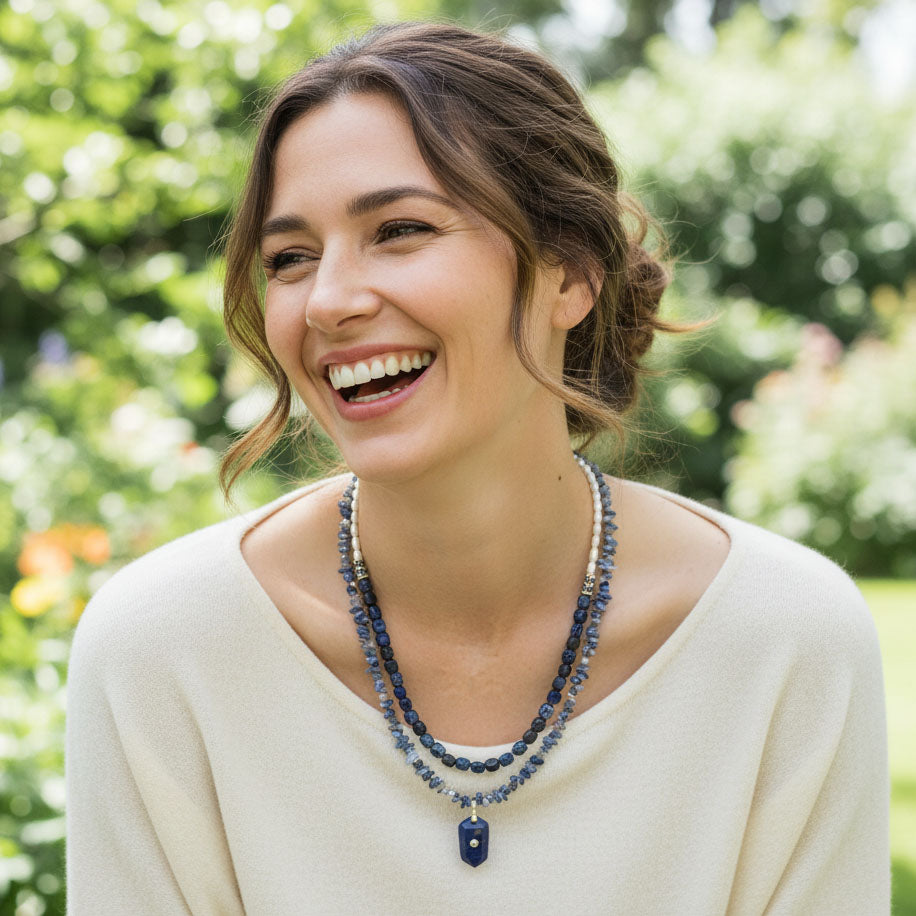 Model wearing blue lapis lazuli and sodalite layered necklace in garden