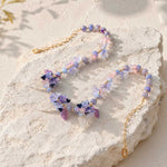 Butterfly Bloom Garden Necklace with Glass Flowers, Resin Butterflies and Hand-Painted Porcelain Beads on a stone surface