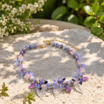 Butterfly Floral Statement Necklace with Glass Blossoms on a stone surface with greenery in the background