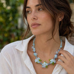 Blue butterfly floral statement necklace worn on model in natural garden setting