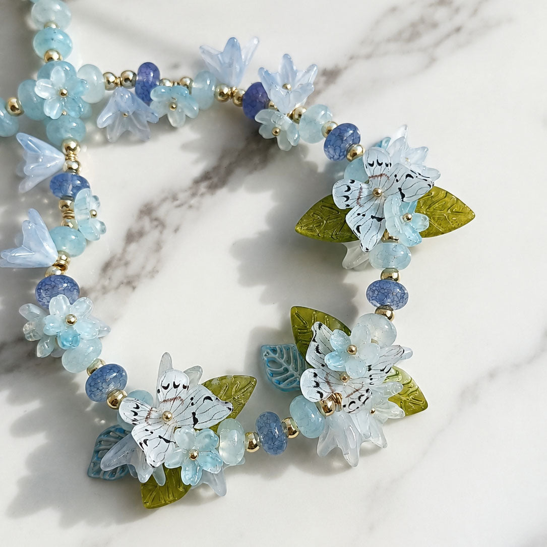 Necklace with floral and butterfly designs on a marble surface