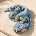 Close-up of artisan pleated scarf necklace featuring hand-painted porcelain beads, woven rattan beads and a pearl magnetic clasp