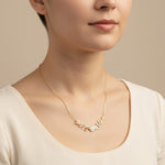 Necklace with floral design worn by a person against a neutral background