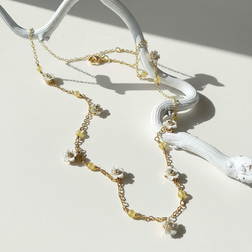 Delicate gold necklace with floral elements on a white surface