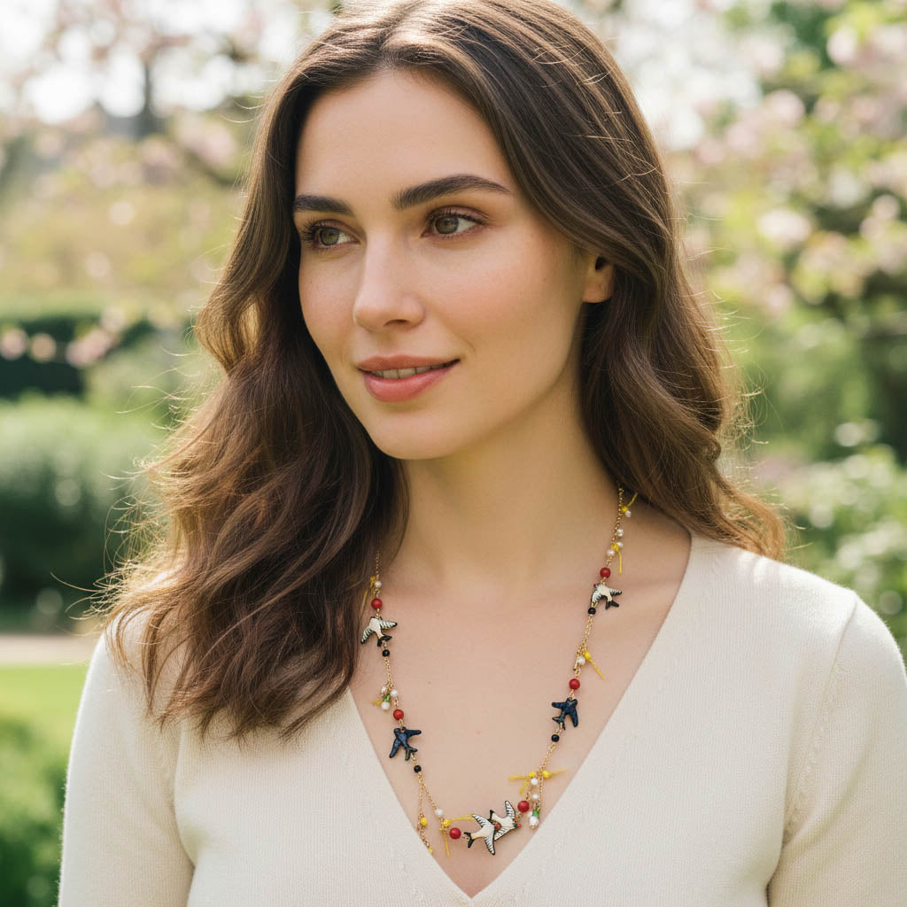 Model wearing handpainted swallow necklace outdoors in sunlight.